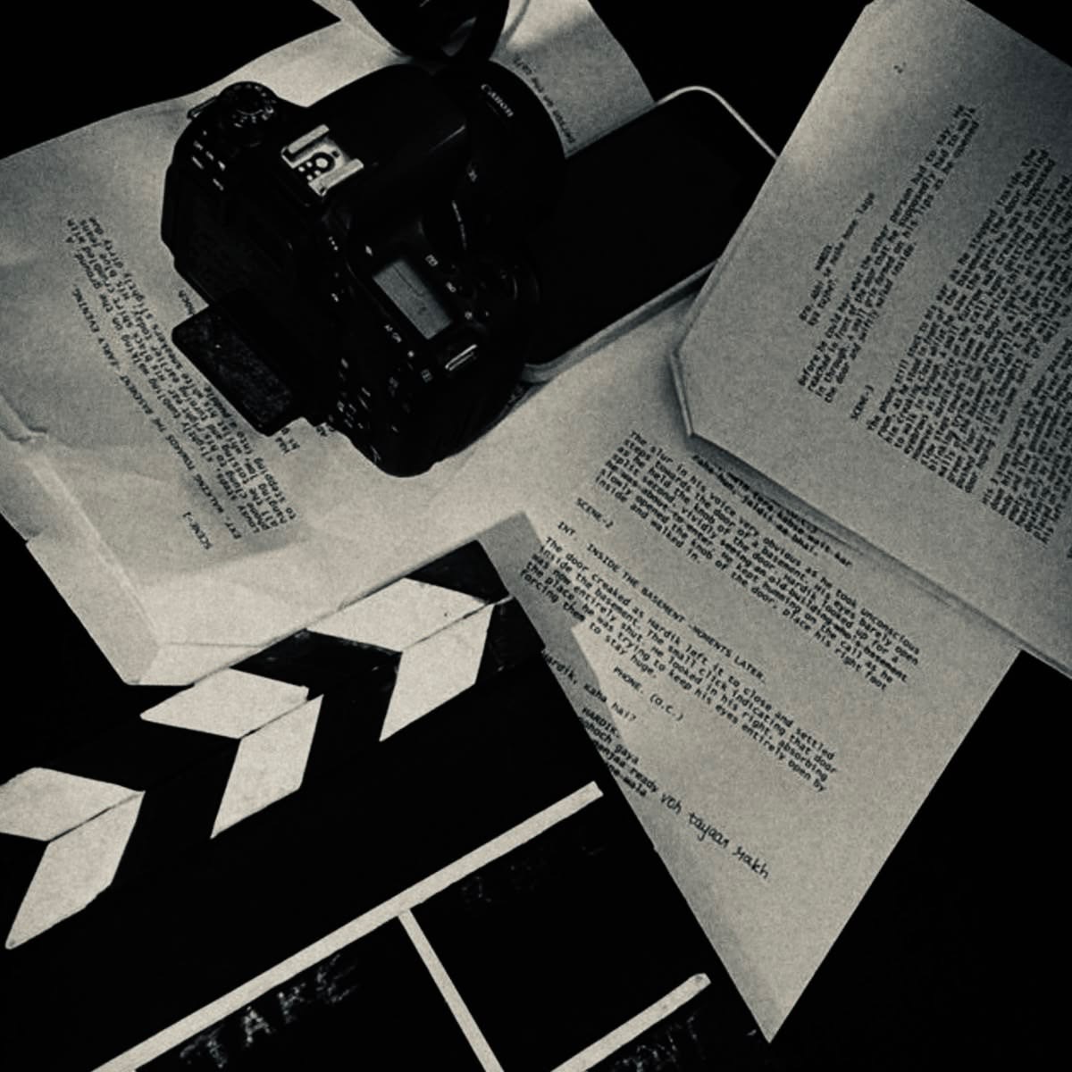 A camera resting on screenplay pages beside a clapperboard
